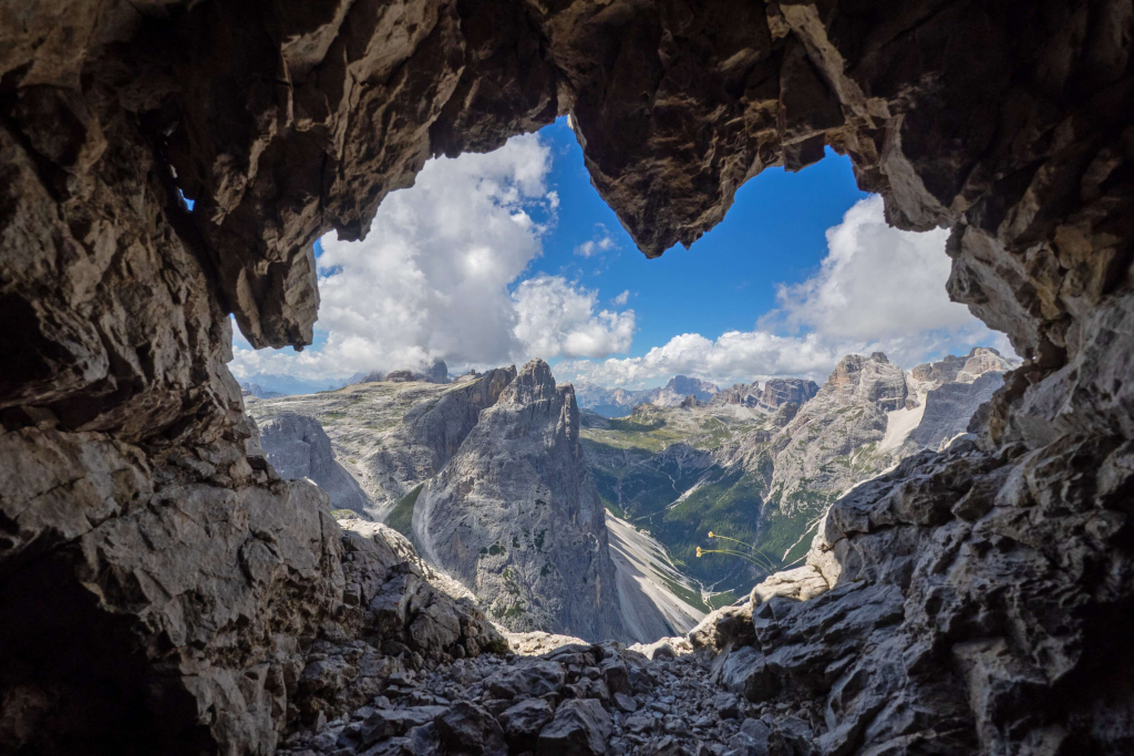 Blick durch einen Felsen auf die majestätischen Karnischen Dolomiten und den blauen Himmel.