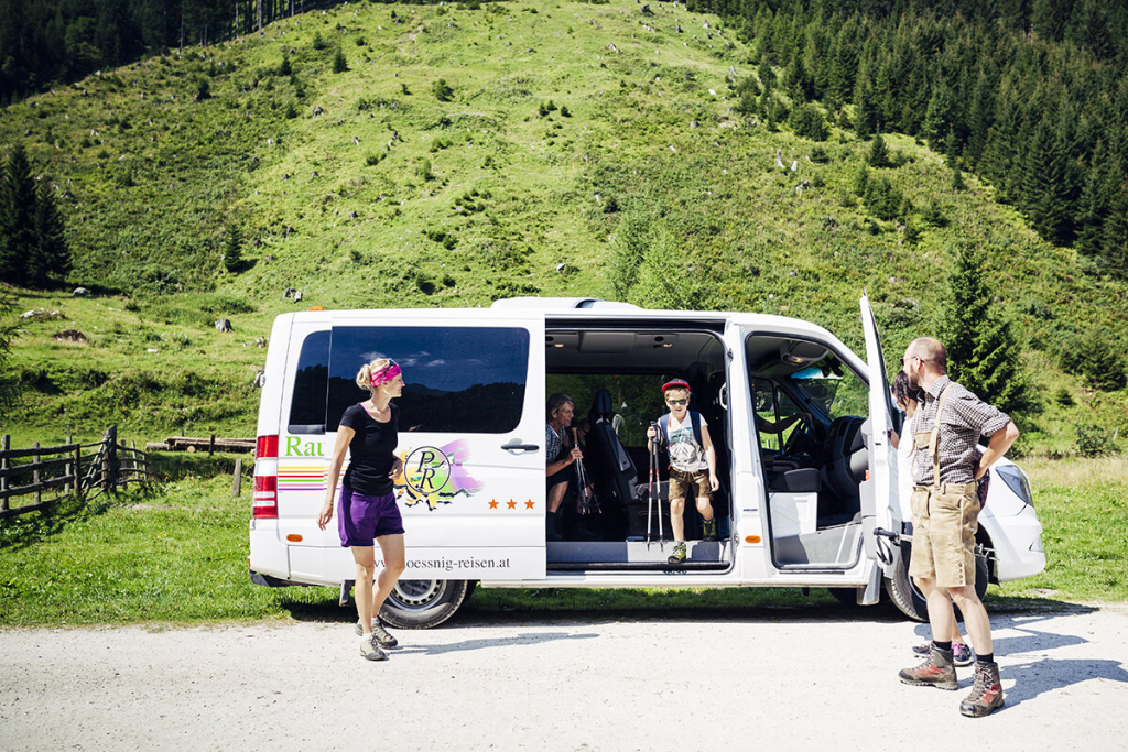 Familie steigt aus Reisebus in Berglandschaft zum Wandern aus